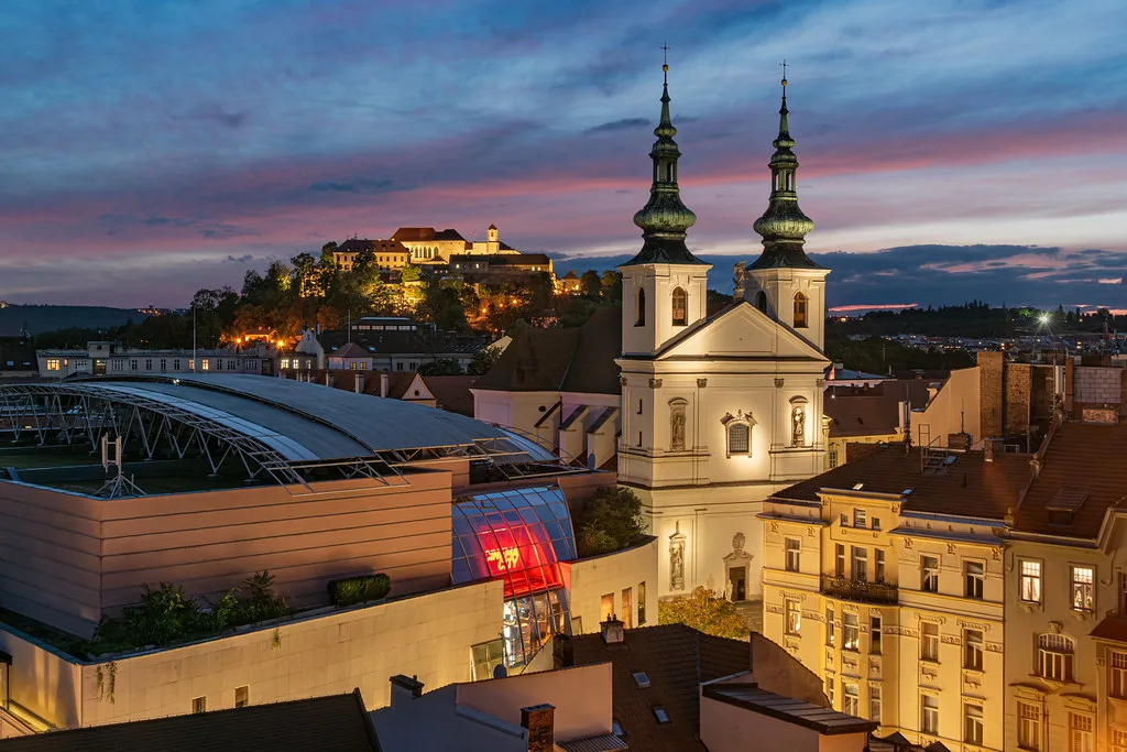St. Michael's Church in Brno at dusk, with Špilberk Castle on the hill behind