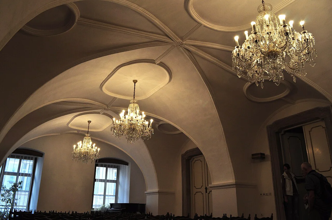 A vaulted hall with chandeliers inside Brno's Old Town Hall.