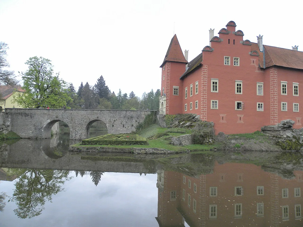 The stone bridge leading to Červená Lhota Castle, reflected in the pond.