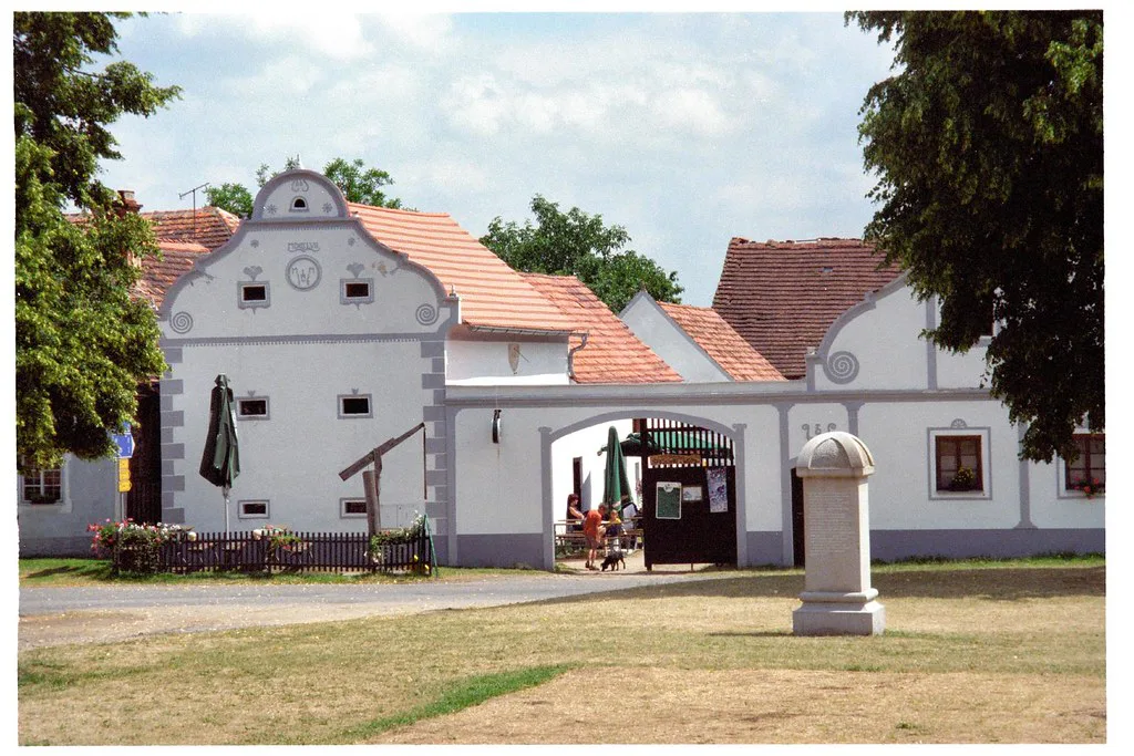 Farmhouses with white gabled facades on the village green in Holašovice