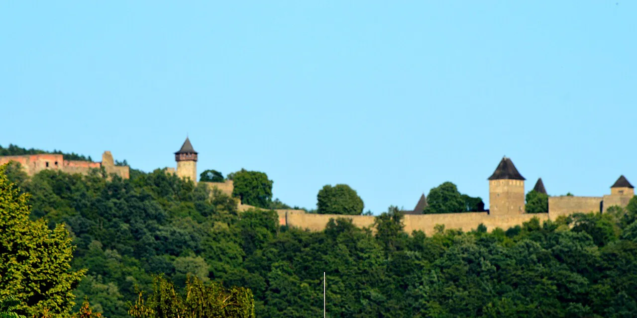 The walls of Helfštýn Castle along its wooded hilltop.