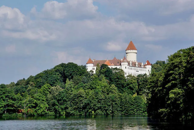 Konopiště Castle above the wooded lakeshore.