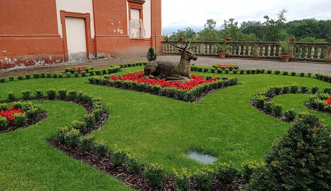 A red deer sculpture and flower beds in the courtyard of Opočno Castle.