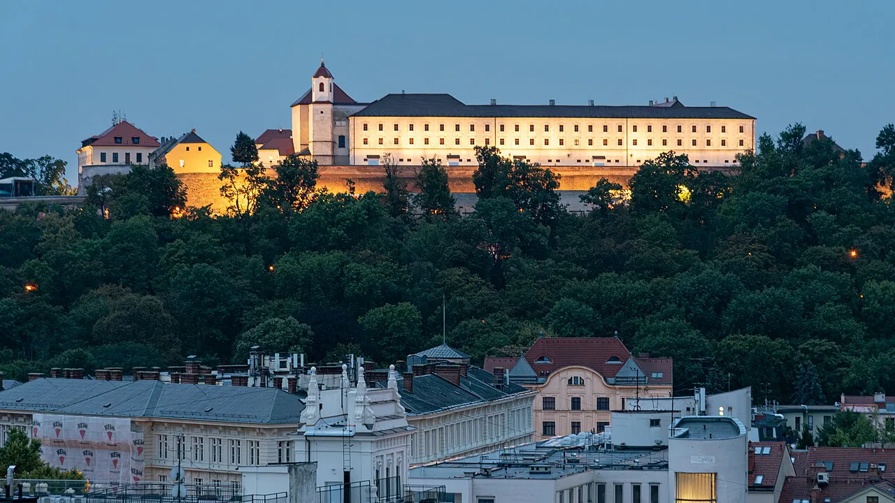 Špilberk Castle on its wooded hill above Brno at dusk.