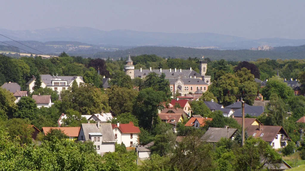 Radimovice village with Sychrov Castle among the trees, hills on the horizon.