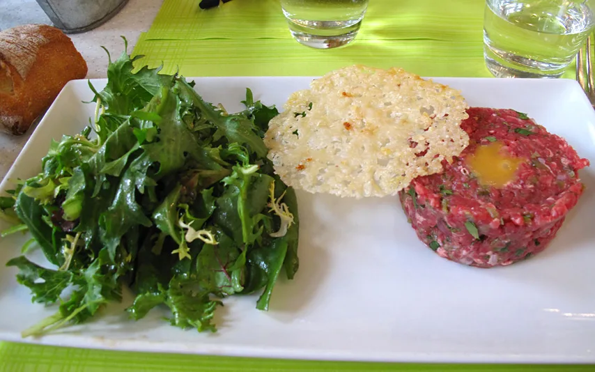 Steak tartare topped with egg yolk, served with arugula salad.