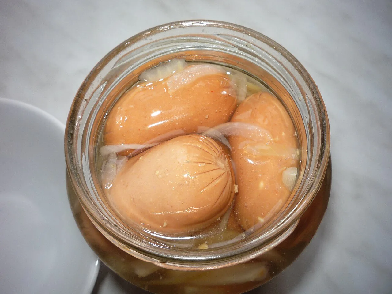 Utopenci, pickled sausages with onion, in a glass jar.