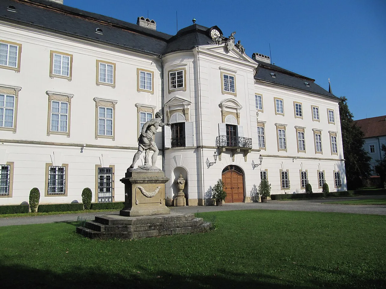 The rear facade of Vizovice Castle with a gladiator statue in front.